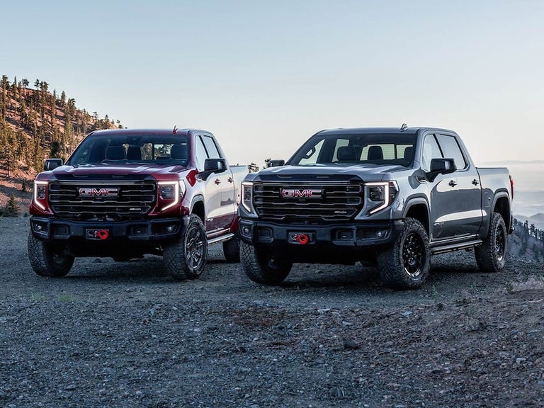 Front View of the GMC Sierra AT4 and the AT4X Next to Each Other with Mountains in the Distance